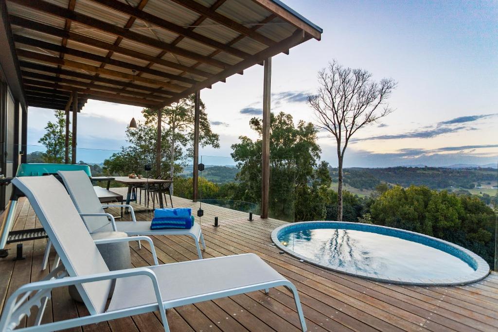 um deque com uma piscina, cadeiras e uma mesa em Byron Hinterland Villas em Clunes