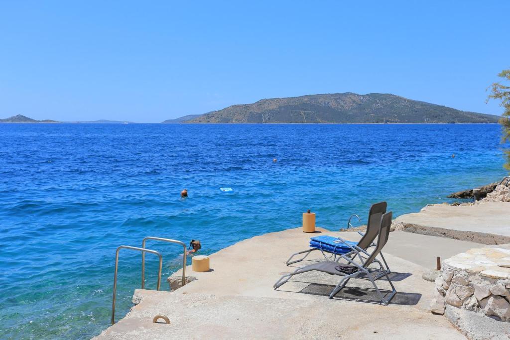 a pair of chairs sitting on the edge of the ocean at Apartment Okrug Donji 16657b in Okrug Donji