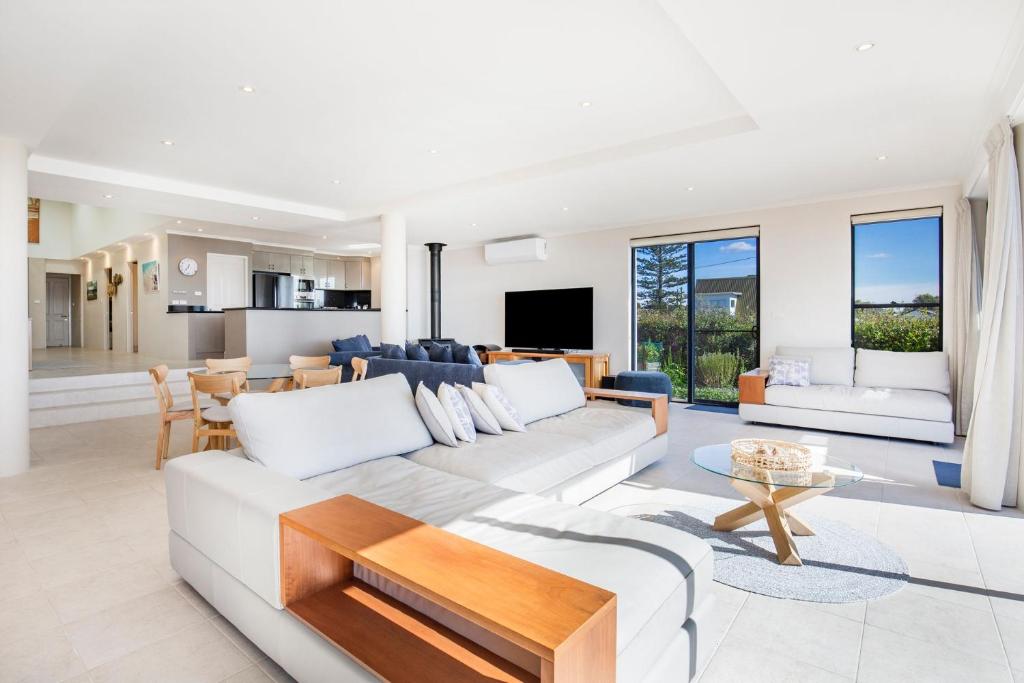a living room with a white couch and a table at Eclipse Absolute Beachfront with Stunning Views in Culburra Beach