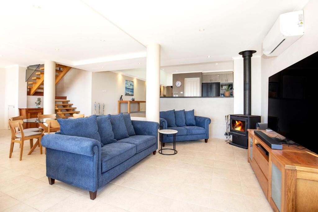a living room with two blue couches and a fireplace at Eclipse Absolute Beachfront with Stunning Views in Culburra Beach