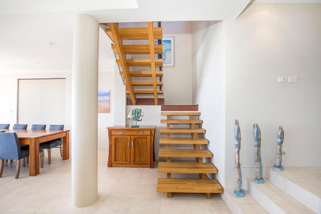 a wooden staircase in a room with a table at Eclipse Absolute Beachfront with Stunning Views in Culburra Beach