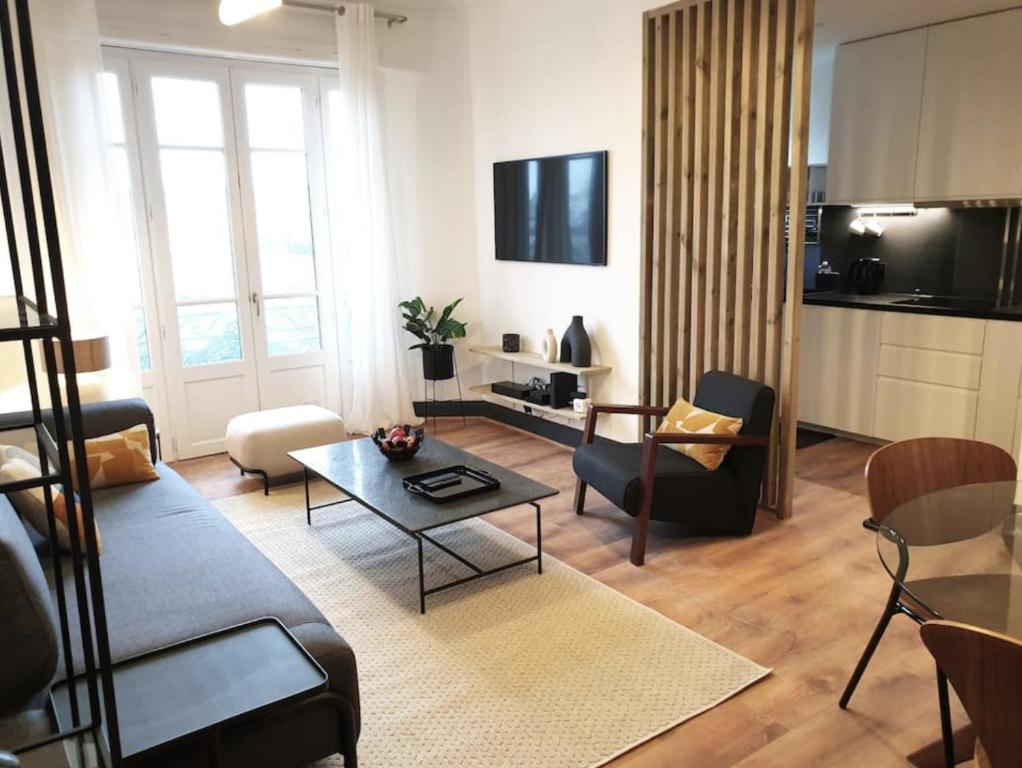a living room with a couch and a table at Vichy : Le 5e - Appartement design dans un ancien palace in Vichy