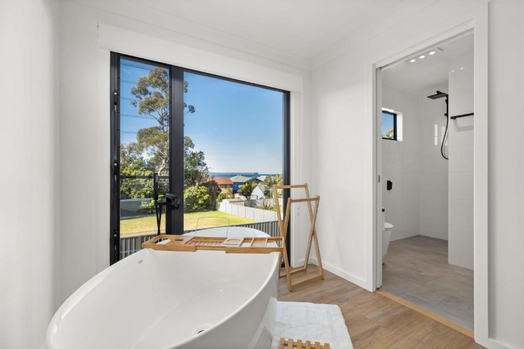 a white bathroom with a tub and a large window at Bella Vita by Experience Jervis Bay in Vincentia