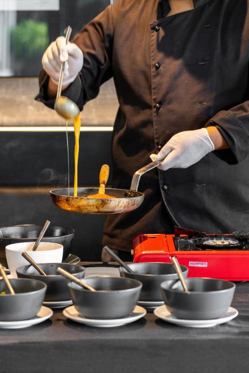 A chef prepares food at a live cooking station with bowls and a portable burner.