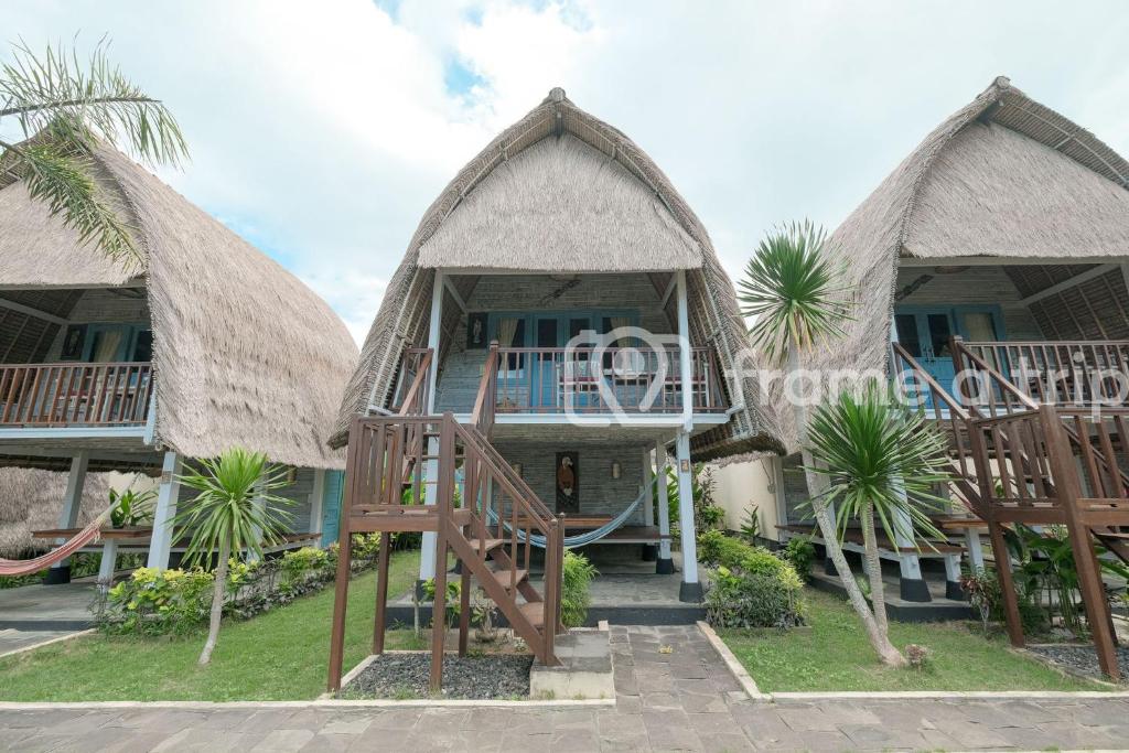 un complejo con 2 casas de campo con techo de paja y palmeras en Dream Beach Kubu & SPA by ABM, en Nusa Lembongan