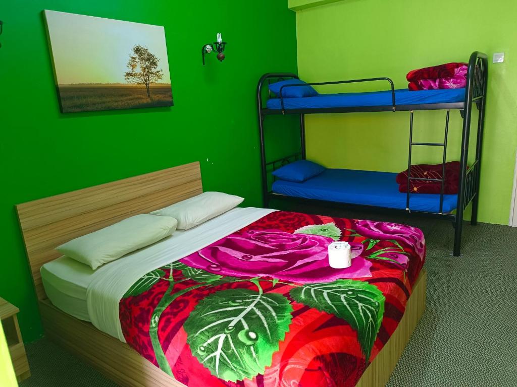 a bedroom with a bed with a green wall at CH TRAVELLERS INN in Tanah Rata