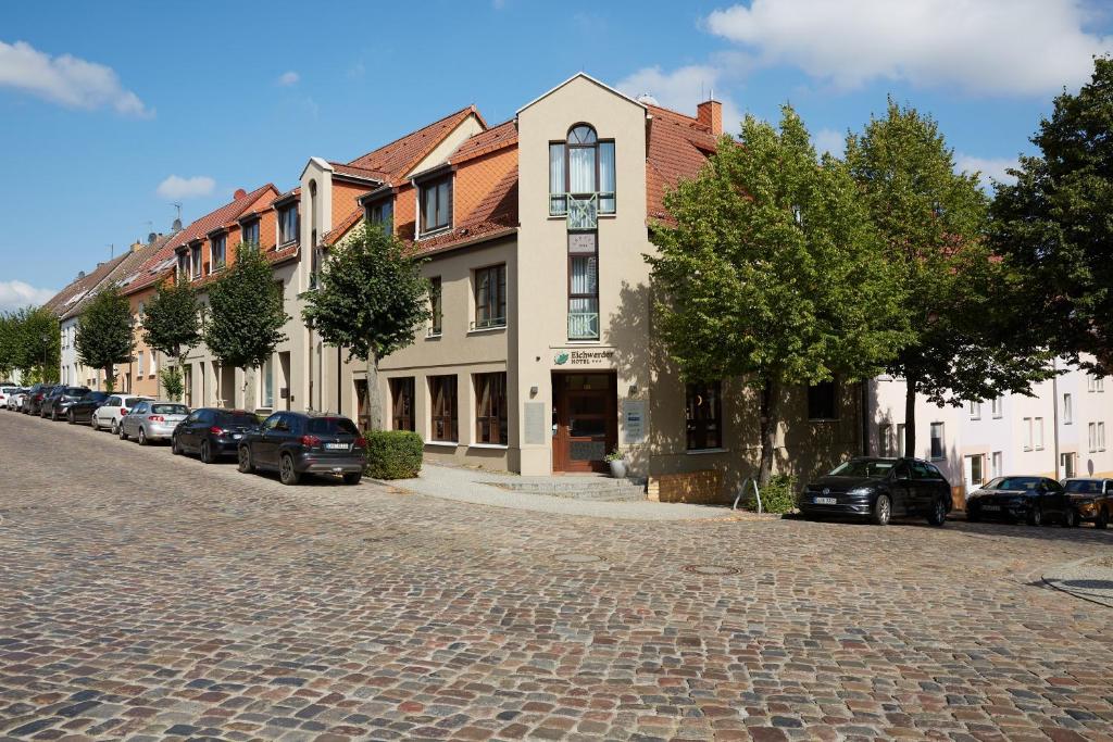 a cobblestone street with cars parked in front of buildings at Hotel garni "Zum Eichwerder" in Templin