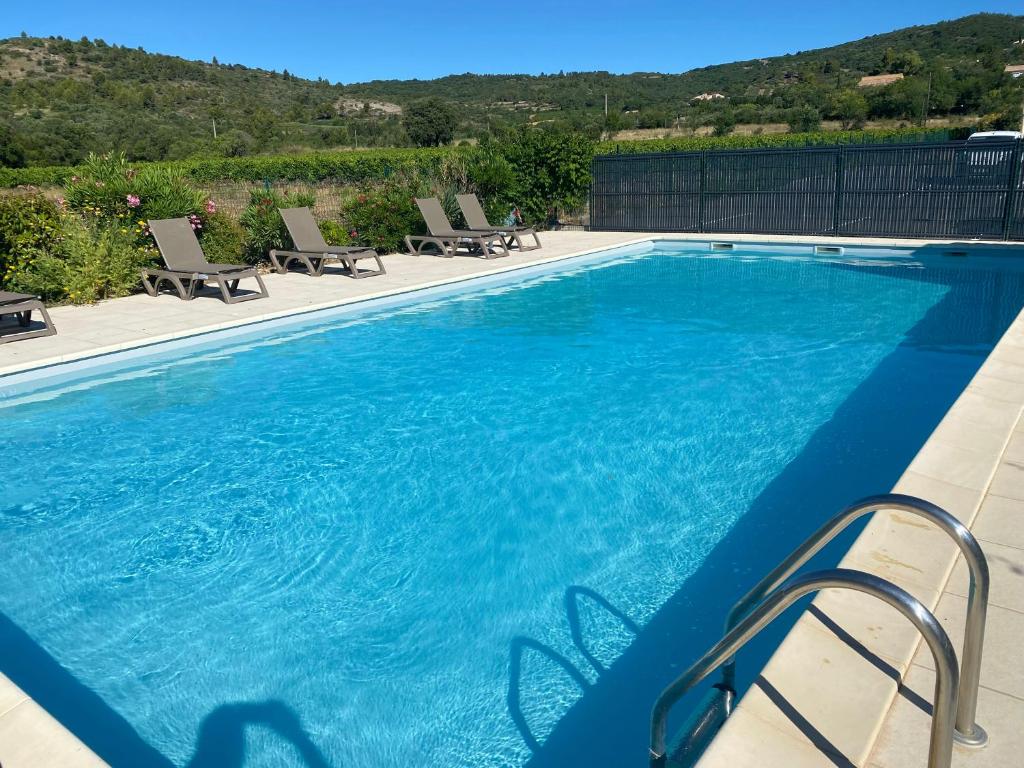 a large swimming pool with blue water and chairs at Appartement entre lac et mer avec piscine in Péret