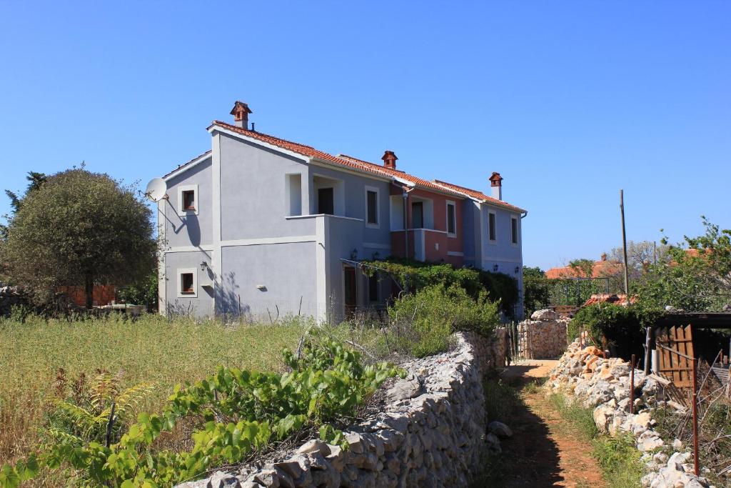 una casa en una colina con una pared de piedra en Apartments by the sea Ilovik, Losinj - 8075 en Ilovik