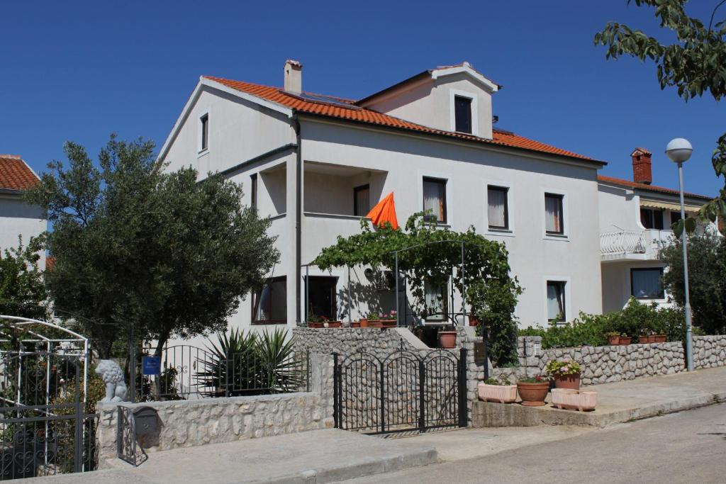 a white house with a fence in front of it at Apartments with a parking space Mali Losinj (Losinj) - 8090 in Mali Lošinj