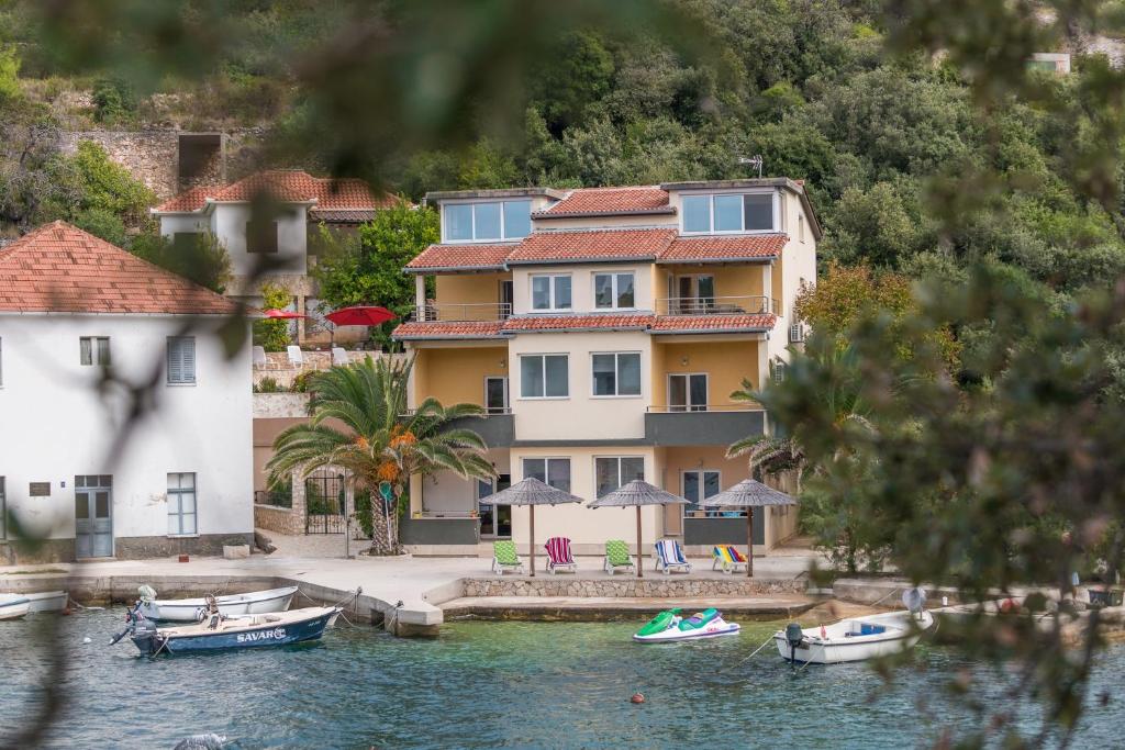 a house on the water with boats in front of it at Apartments by the sea Savar, Dugi otok - 8128 in Brbinj