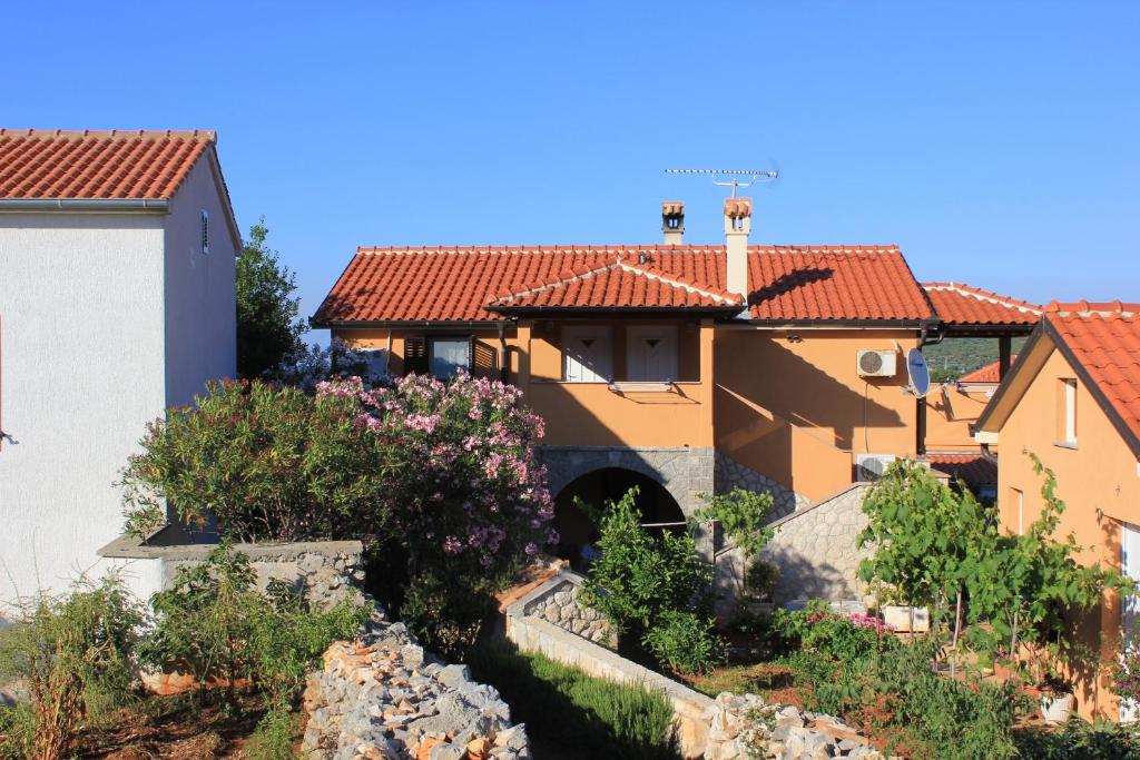 ein Haus mit roten Dächern und einem Garten mit Blumen in der Unterkunft Apartments with WiFi Ilovik, Losinj - 8078 in Ilovik