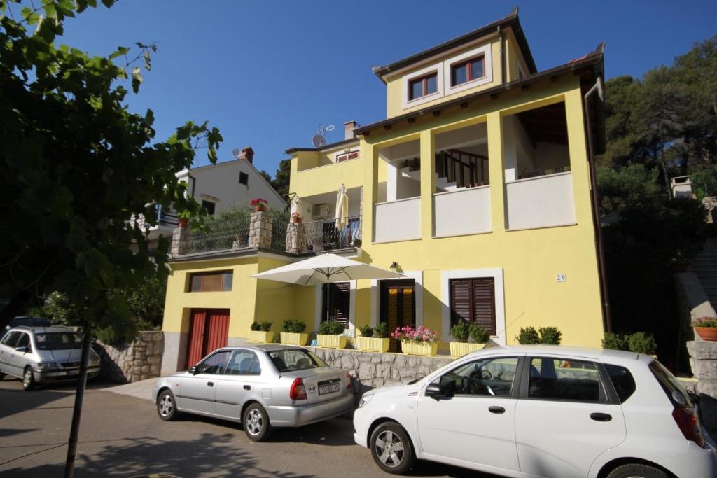 two cars parked in front of a yellow house at Apartments by the sea Mali Losinj (Losinj) - 8093 in Mali Lošinj