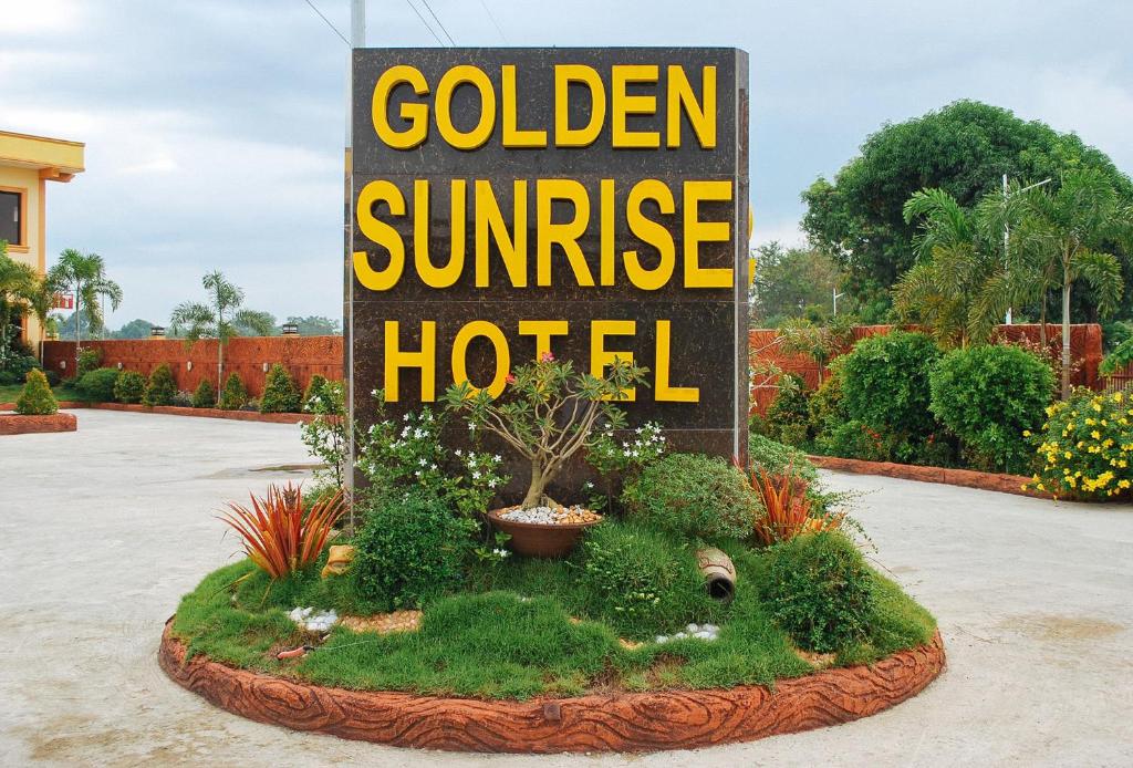 a sign for a golden sunrise hotel in a garden at Golden Sunrise Hotel I by RedDoorz 