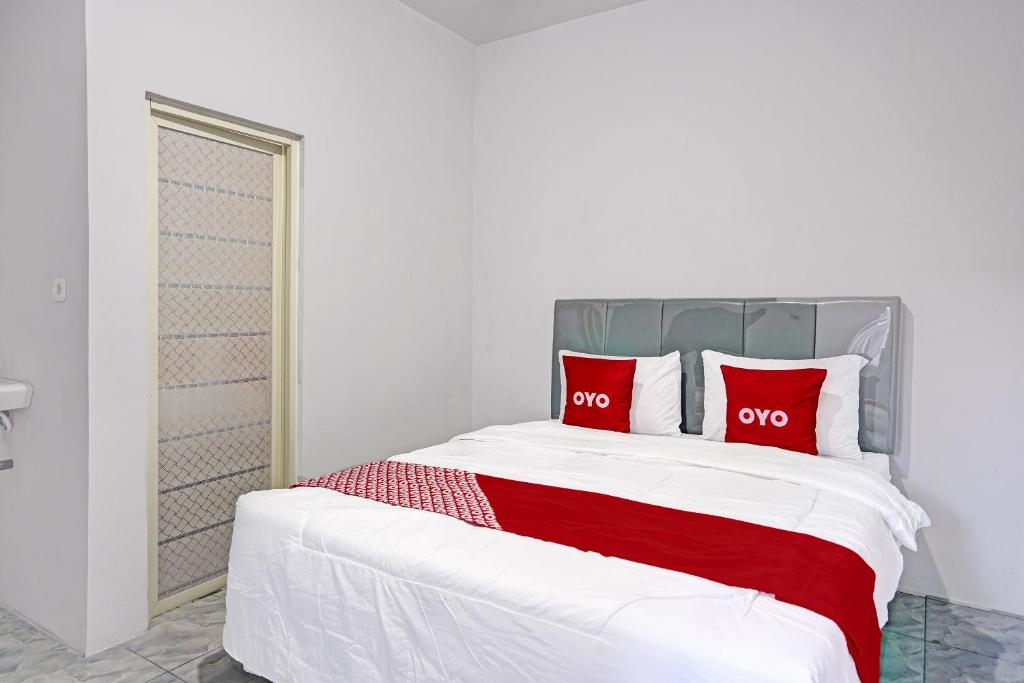 ein Schlafzimmer mit einem großen Bett mit roten Kissen in der Unterkunft OYO LIFE 91594 Bungah Residence Syariah in Gresik