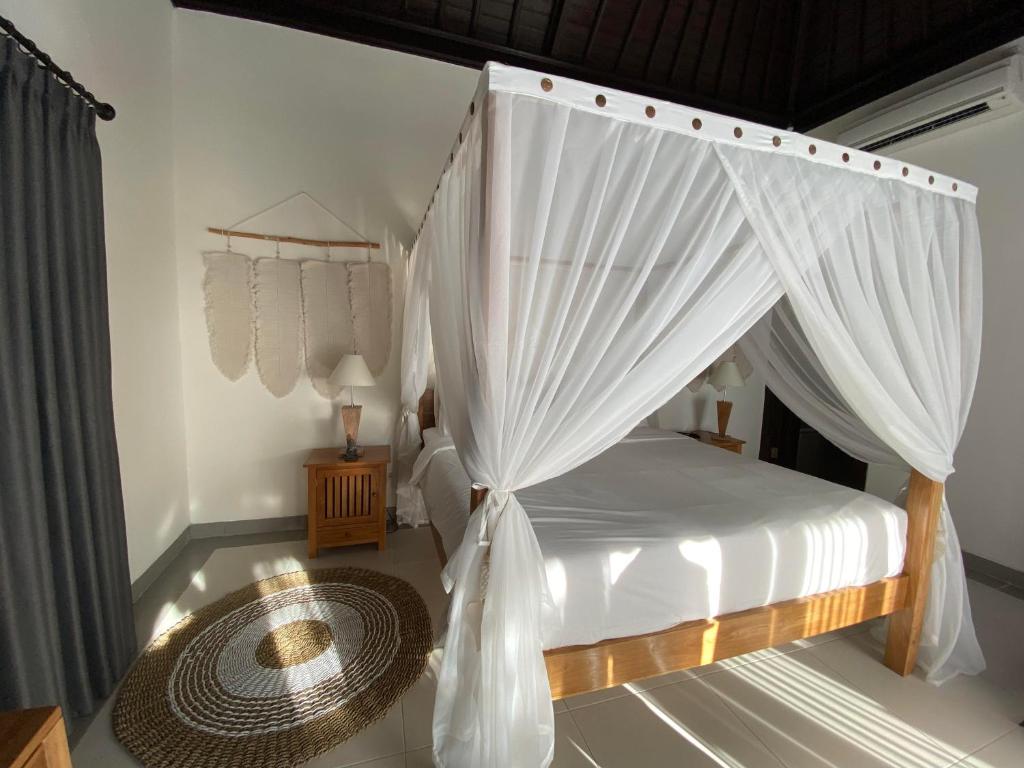 a bedroom with a canopy bed with white curtains at The Palms Canggu in Canggu