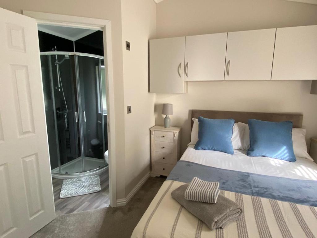 1 dormitorio con cama con almohadas azules y ducha en Augusta lodge, en Wisbech