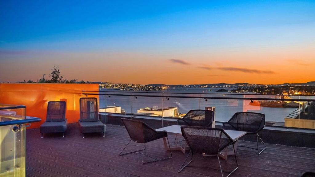a deck with a table and chairs on a balcony at Exclusive apartment, sea view to Oslo fjord, located on water in Oslo center in Oslo