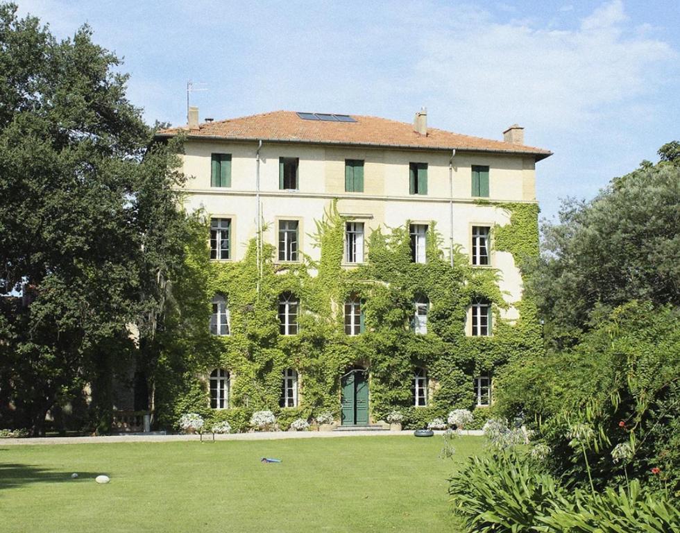 a large white building with green ivy on it at Château de Saü in Thuir