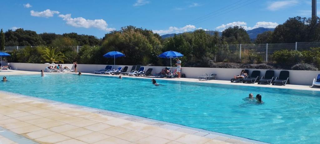 una grande piscina con persone in acqua di Maison duplex 2 chambres, avec jardin, 800m plage a Belgodère
