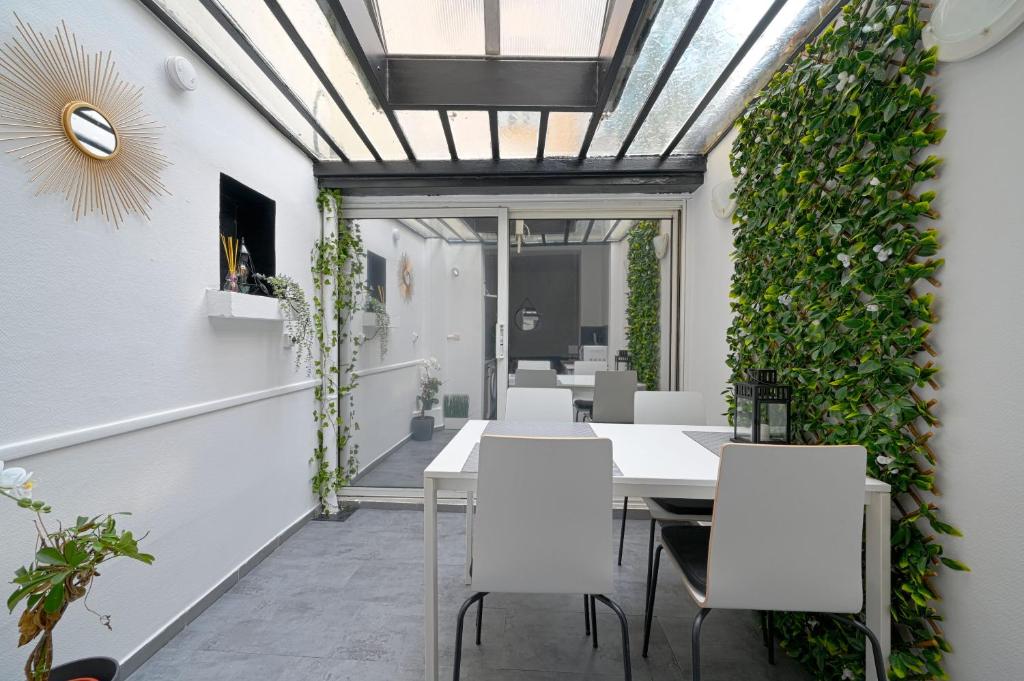 een eetkamer met witte stoelen en een groene muur bij Studio chez Thomas in Parijs