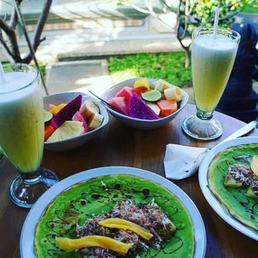 a wooden table topped with plates of food and drinks at Sudiana House in Ubud