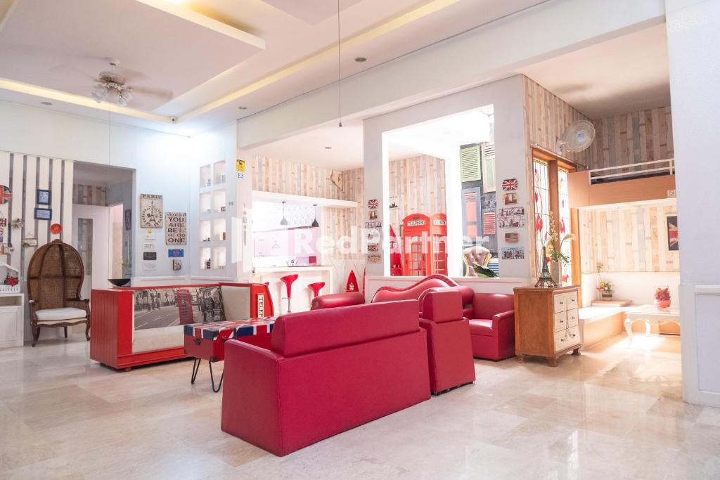 uma sala de estar com mobiliário vermelho e uma grande janela em Londres Bed and Breakfast RedPartner near Gembira Loka Zoo em Yogyakarta