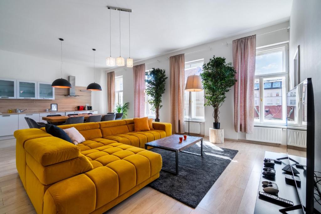 een woonkamer met een gele bank en een tafel bij Centrum Apartments Pstrossova in Praag