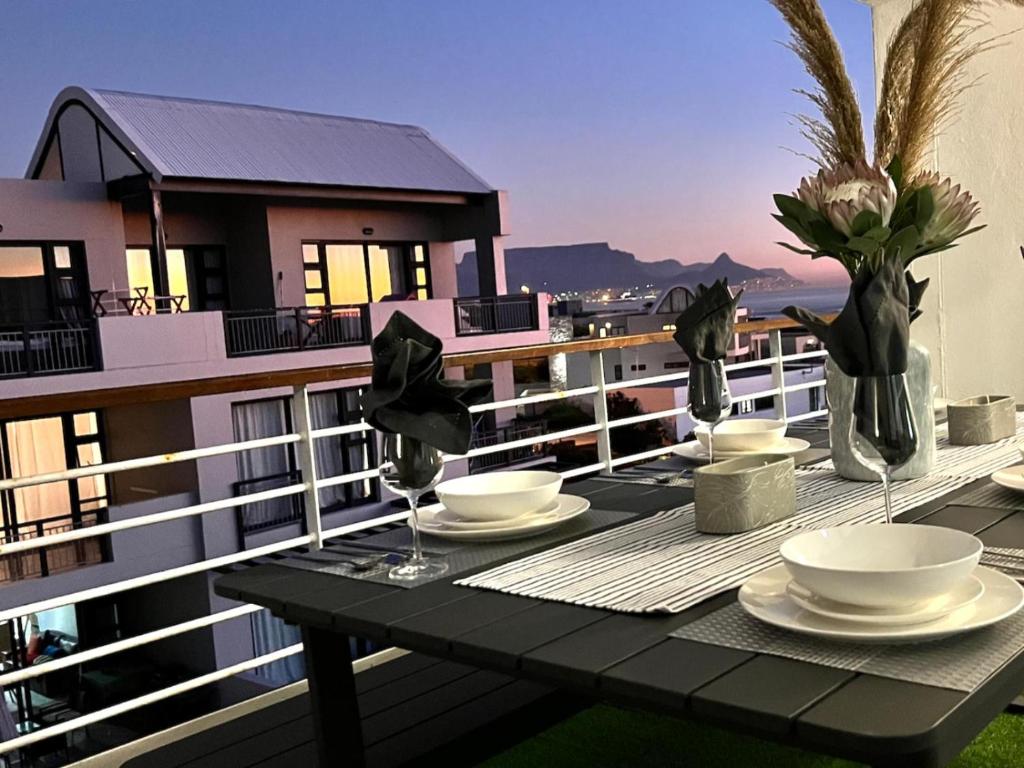 a table with plates and bowls on a balcony at Azure 213-Luxury 2 Bedroom Apartment with an Inverter & Battery Backup Power in Big Bay