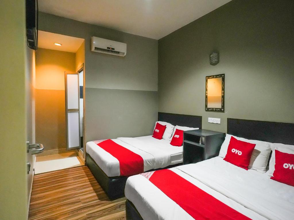 Habitación de hotel con 2 camas con almohadas rojas en OYO 89950 365 Nice Stay en Miri