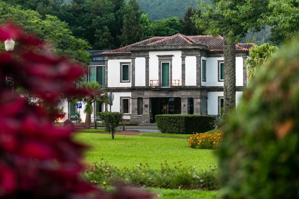 ein großes weißes Haus mit einem Hof mit Blumen in der Unterkunft Octant Furnas in Furnas