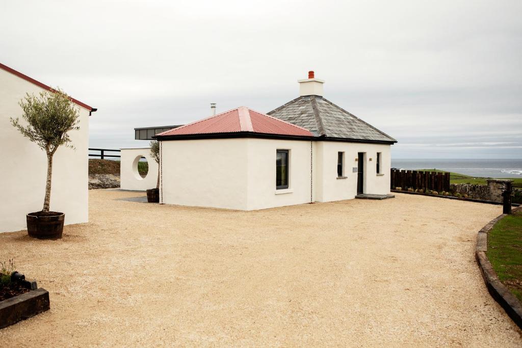 un pequeño edificio blanco con techo rojo en Gate Lodge@White Strand en Miltown Malbay