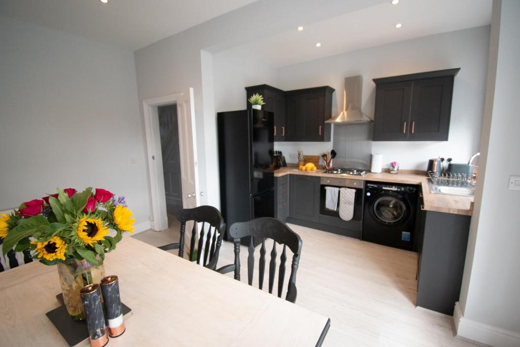 una cocina con una mesa con un jarrón de flores. en Ideal Lodgings in Royton en Royton