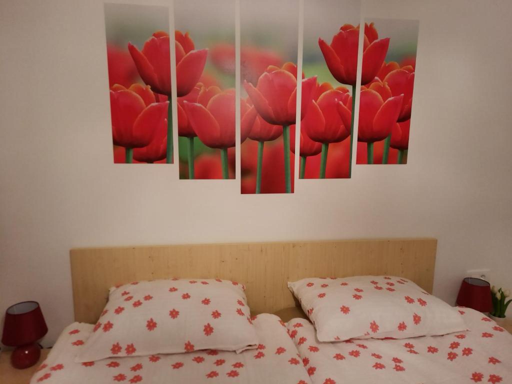 a bedroom with red tulips paintings on the wall at Apartma Rožle in Mojstrana