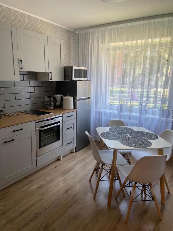 a kitchen with a table and chairs and a kitchen with white cabinets at Nice to stay in Visaginas