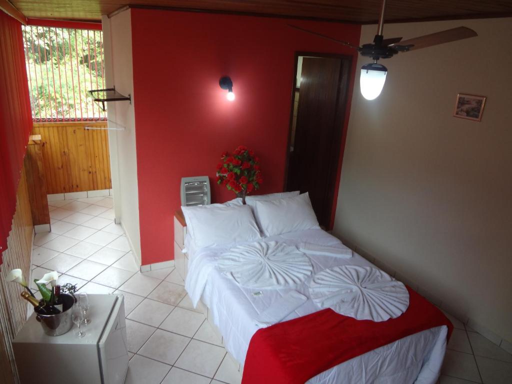 a bedroom with a bed with a red wall at Pousada do Bezerra in Alto Caparao