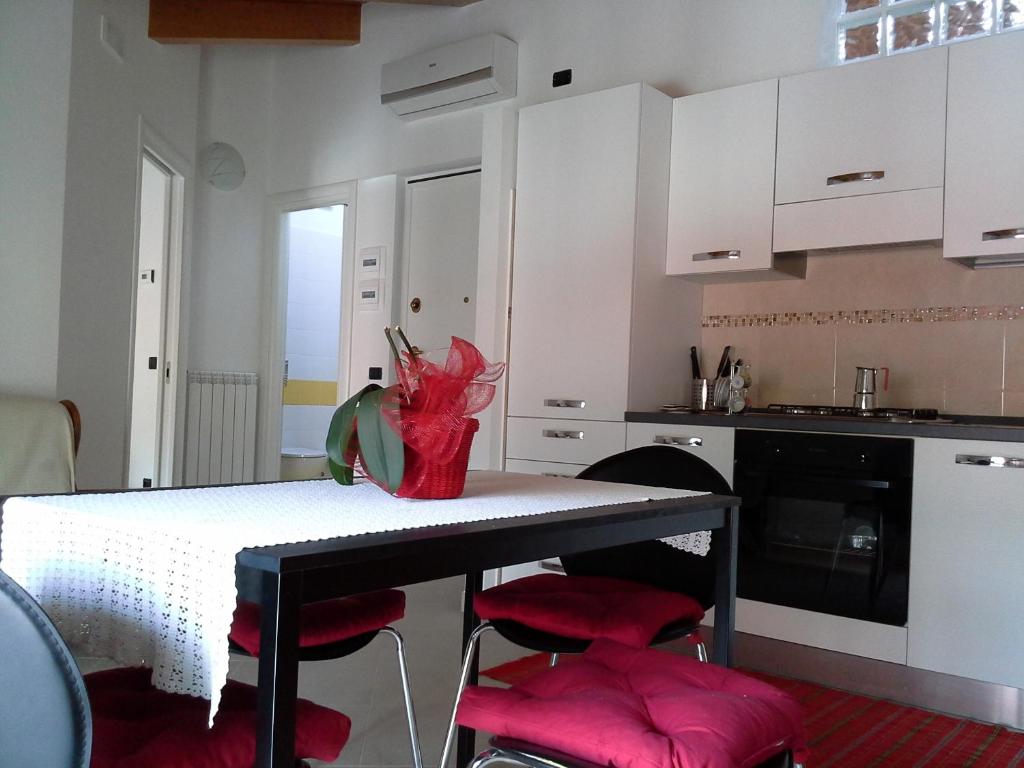 kuchnia ze stołem z czerwonymi krzesłami i białymi szafkami w obiekcie Casa vacanze The Flea's Home w mieście Fondi