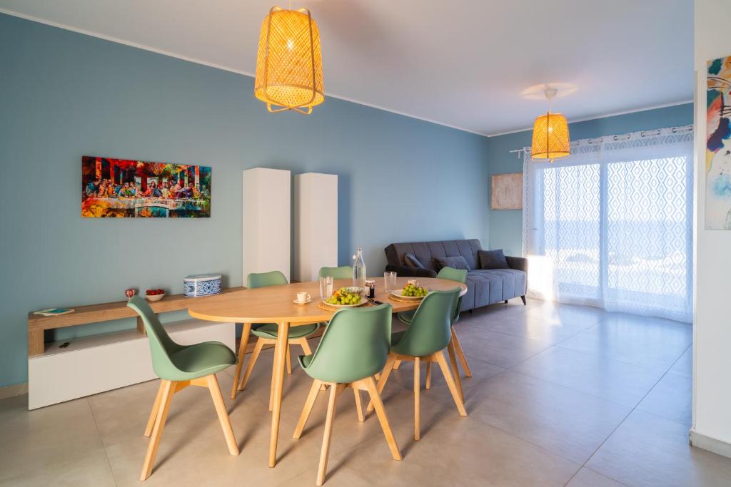 een eetkamer met een houten tafel en groene stoelen bij Pilar Apartment Vista Mare in Portopalo