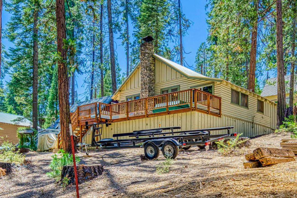 une maison dans les bois entourée d'une terrasse dans l'établissement Alpine Cottage, à Shaver Lake