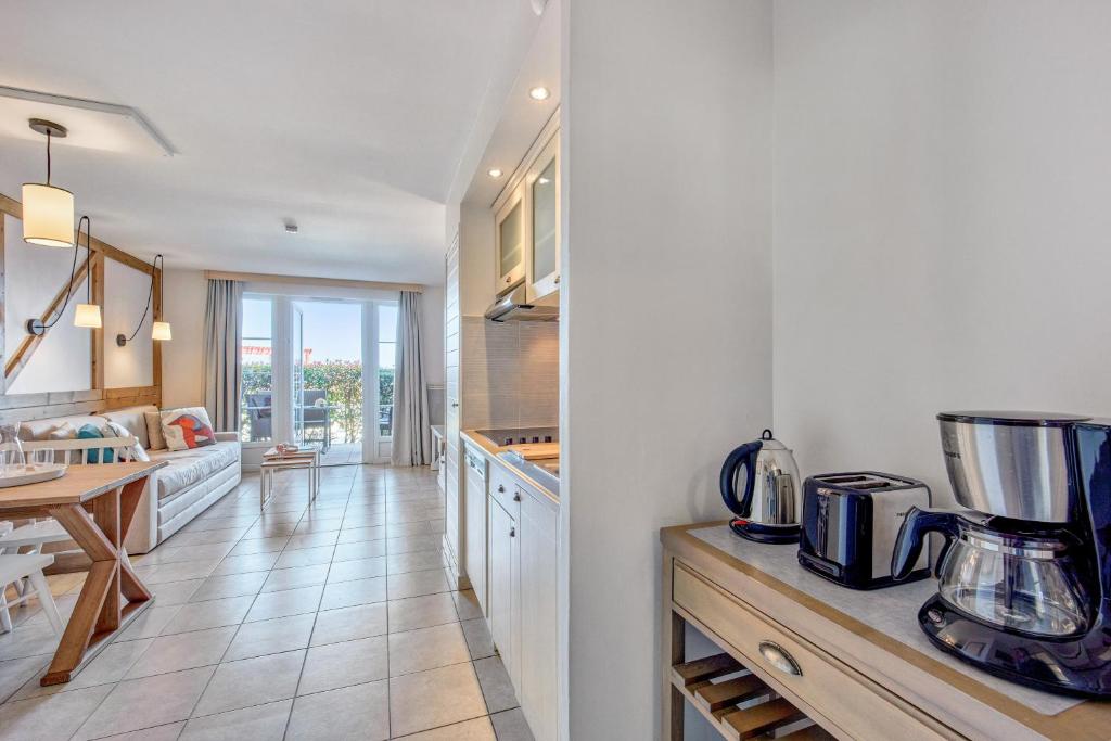 a kitchen with white cabinets and a table and a counter top at Pierre & Vacances Premium Residence & Spa Houlgate in Houlgate