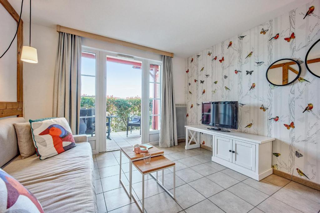 a living room with a couch and a tv at Pierre & Vacances Premium Residence & Spa Houlgate in Houlgate