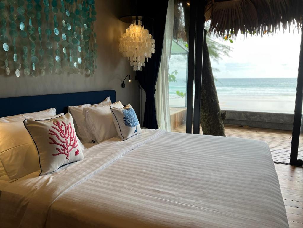 a bedroom with a bed with a view of the ocean at Sealord Naithon Beachfront Villa in Nai Thon Beach