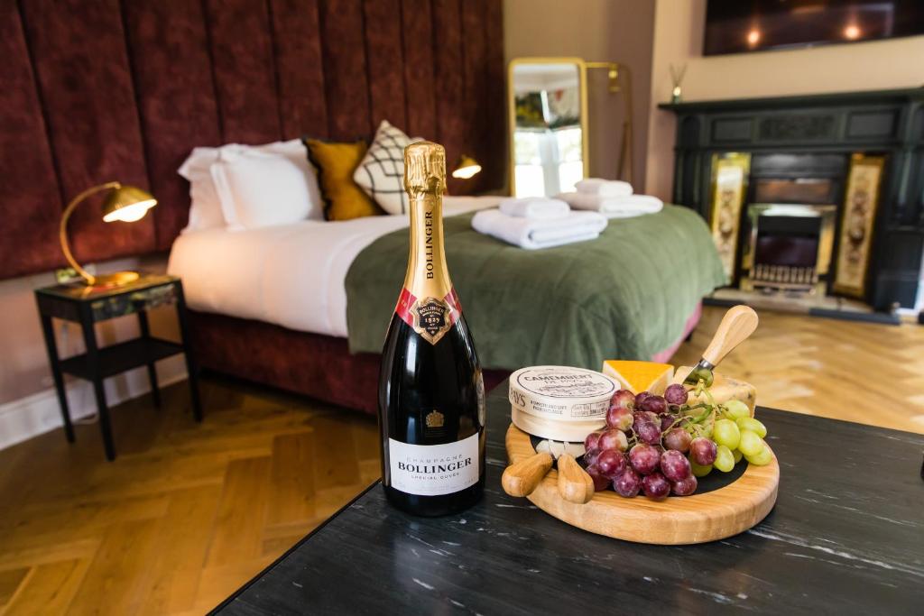 eine Flasche Champagner und Trauben auf dem Tisch in einem Hotelzimmer in der Unterkunft Dragon Villas by Maison Parfaite - Luxury Studios & Apartments - Harrogate in Harrogate