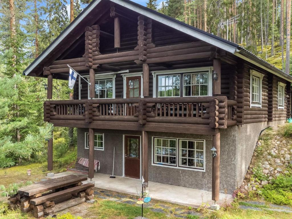 uma cabana de madeira com um deque na floresta em Holiday Home Sarvitupa by Interhome em Kangashäkki