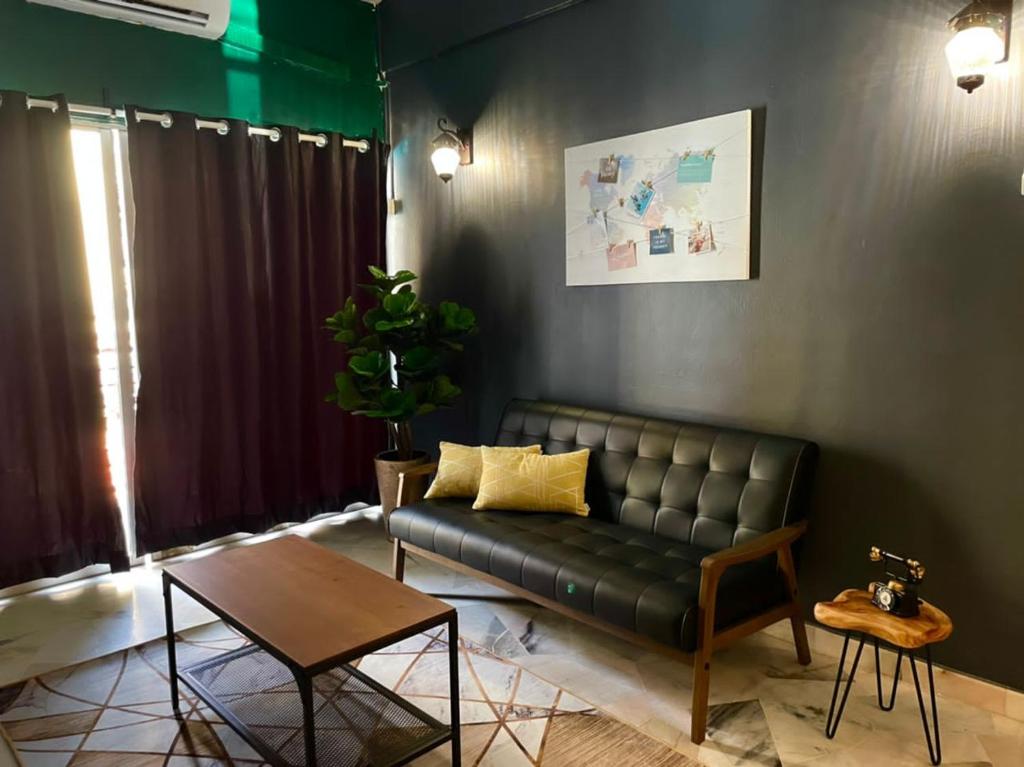 a living room with a leather couch and a table at The Berlian Guesthouse - Two beedroom Apartment with Pool View in Port Dickson