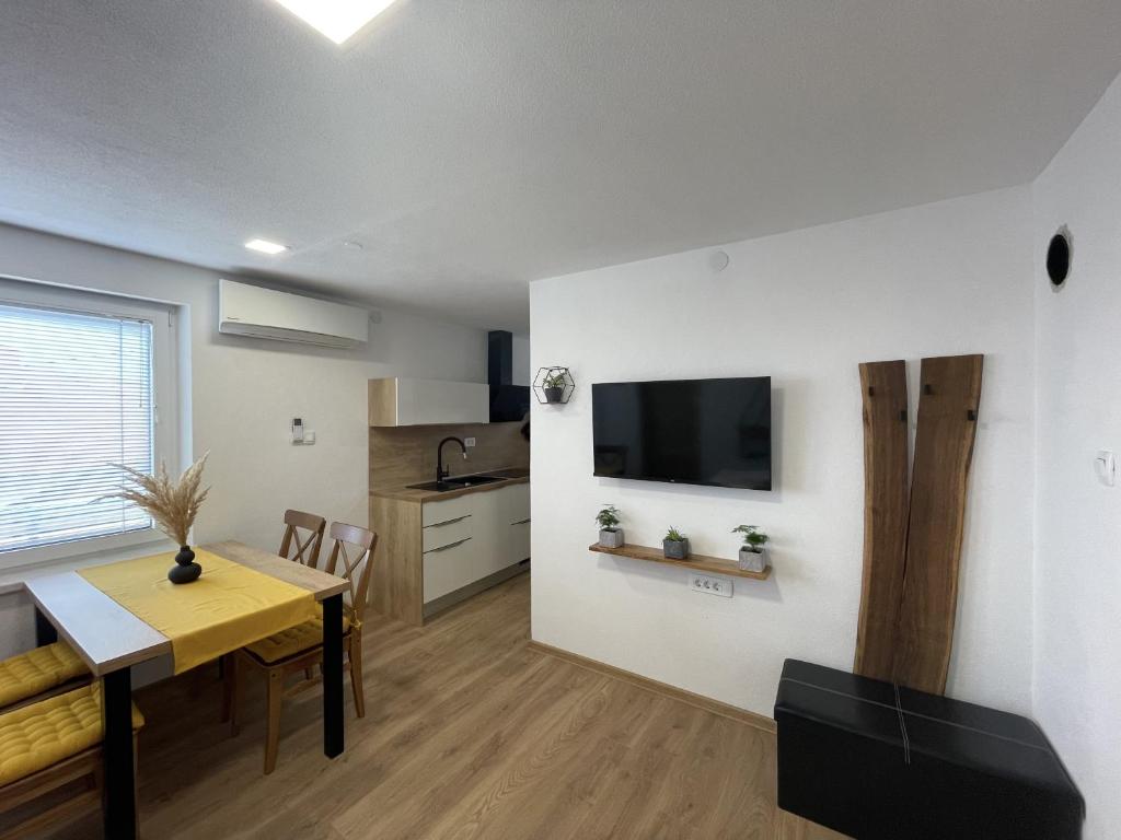 a kitchen and dining room with a table and a television at Apartments and rooms pri Bašlju in Cerkno