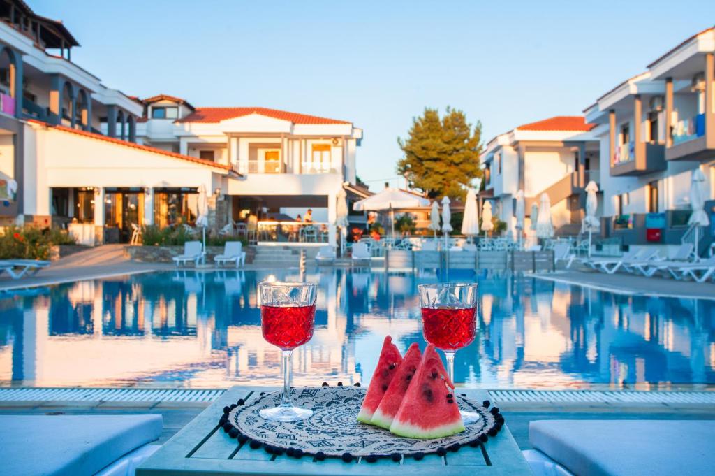 a table with two glasses of wine and a slice of watermelon at Acrotel Lily Ann Village in Nikiti
