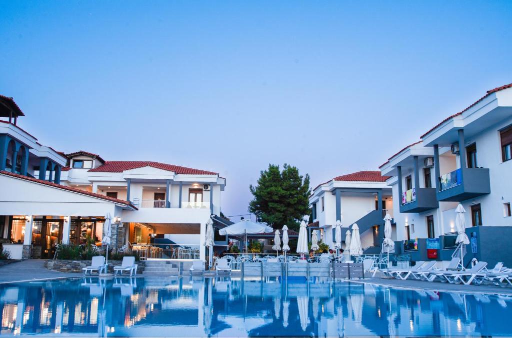 a swimming pool with chairs and buildings at Acrotel Lily Ann Village in Nikiti