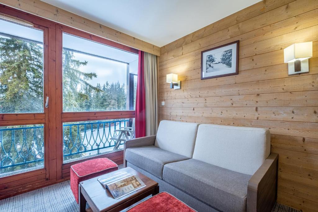 a living room with a couch and a large window at Résidence Pierre & Vacances Le Belmont in Arc 1800