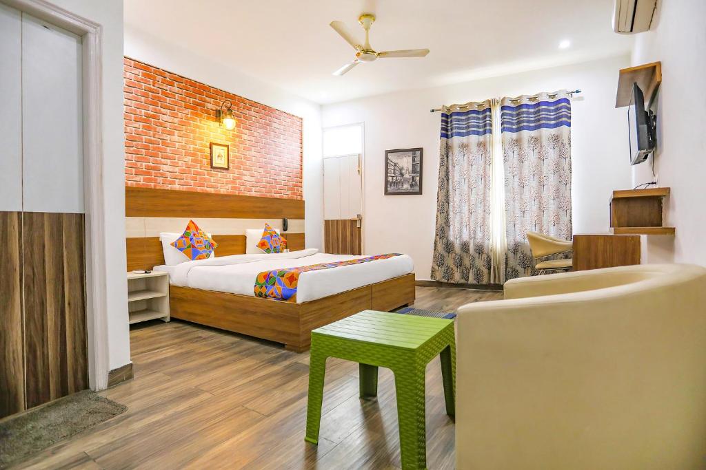 a bedroom with a bed and a chair and a couch at FabHotel Aravali Suites in Gurgaon